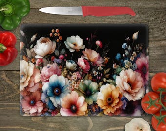 May include: A black cutting board with a floral design featuring pink, white, and blue flowers on a black background.