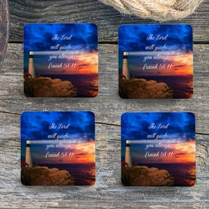 Puede incluir: Conjunto de cuatro posavasos cuadrados con un faro con un haz de luz que brilla sobre el océano al atardecer. El texto "The Lord will guide you always Isaiah 58:11" está impreso en cada posavasos.