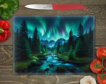 May include: A glass cutting board with a scenic image of a forest with a river and a green and blue aurora borealis in the sky.