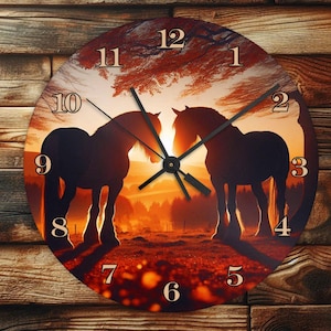 May include: Round wall clock featuring a silhouette of two horses against a sunset backdrop. The clock face has large, easy-to-read numbers and black clock hands. The background is a warm blend of orange, red, and yellow hues, with a wooden texture.
