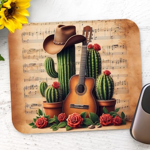 May include: A brown cowboy hat sits atop a guitar with a cactus growing out of the guitar's sound hole. The guitar is surrounded by cacti and red roses on a background of sheet music.