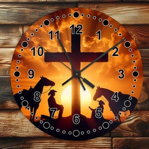May include: A round clock with a sunset background featuring a silhouette of a cross with two figures on horseback praying beneath it. The clock face has Roman numerals and a black hand.