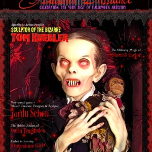 May include: A magazine cover titled Autumn Brilliance Fall 2026 featuring a pale, vampire-like figure with sharp teeth and glowing red eyes holding a small, dark-clothed doll. The text includes Tom Kuebler, Sherrie Taylor, and Jordu Schell.