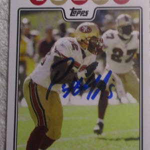 May include: A Topps trading card featuring San Francisco 49ers football player Patrick Willis in a white and gold uniform. The card displays the text 49ERS at the top, the Topps logo, and the name PATRICK WILLIS at the bottom with a blue ink autograph.