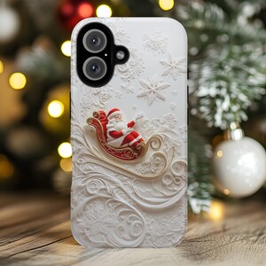 May include: White phone case featuring a 3D relief of Santa Claus in his sleigh, with snowflakes and decorative swirls. Santa is wearing a red suit and hat. The case has a dual-lens camera cutout.
