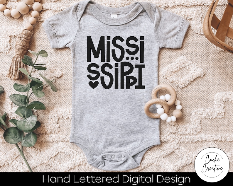 May include: A gray baby onesie with black text that reads "MISSISSIPPI" with a small heart in front of the word "SIPI".