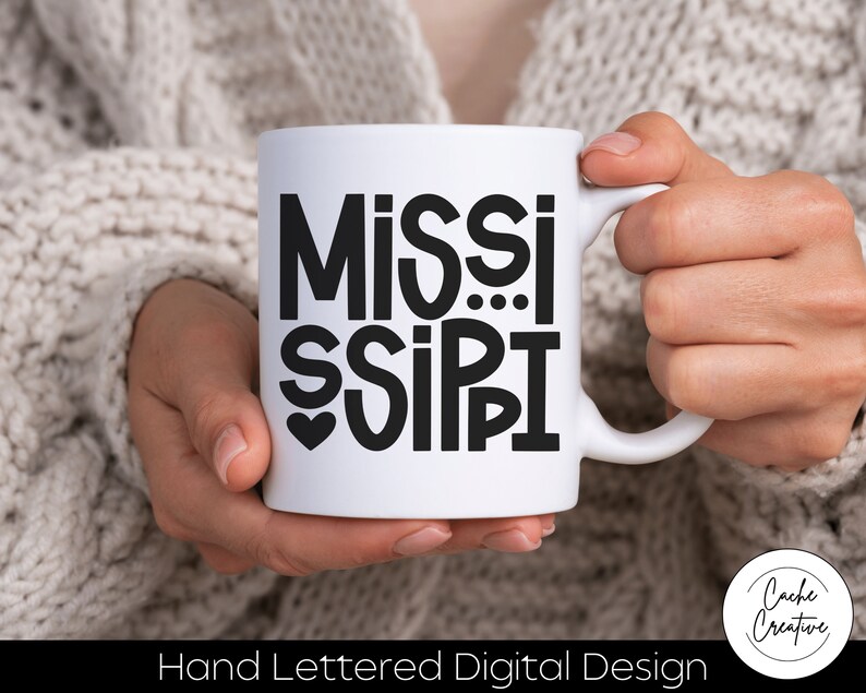 May include: White ceramic mug with a black hand-lettered design that says "MISSISSIPPI" with a heart in the middle of the word "MISSI".