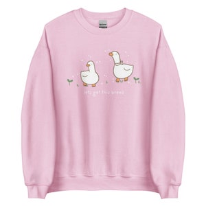 Pastel Pink Whimsical Duck Sweatshirt with a dtg printed design of two ducks surrounded by sparkles, and below it says " lets get this bread"
