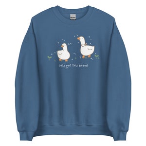 Indigo Blue Whimsical Duck Sweatshirt with a dtg printed design of two ducks surrounded by sparkles, and below it says " lets get this bread"