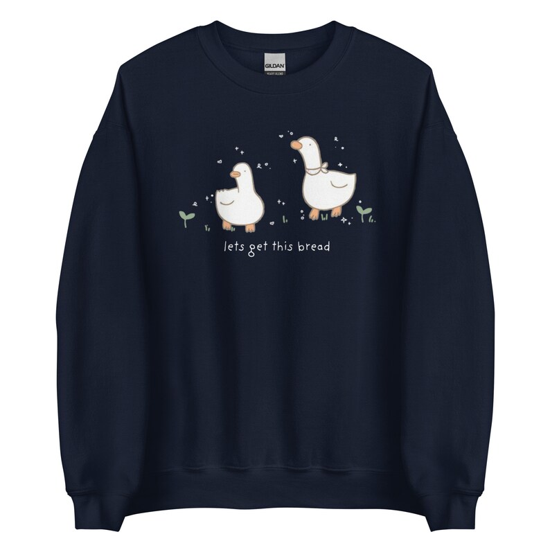 navy Blue Whimsical Duck Sweatshirt with a dtg printed design of two ducks surrounded by sparkles, and below it says " lets get this bread"