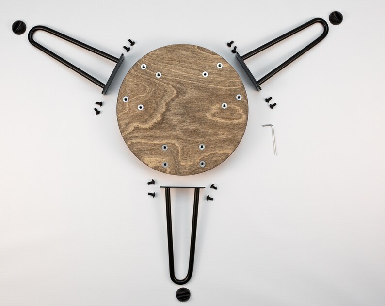 May include: A set of three black metal hairpin legs for a table or chair, with a round wooden tabletop. The legs are attached to the tabletop with screws.