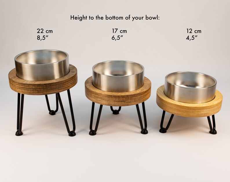 May include: Three stainless steel pet bowls on wooden stands with black metal legs. The bowls are 22 cm, 17 cm, and 12 cm tall.
