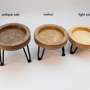 May include: Three wooden trays with black metal legs, each in a different wood stain: antique oak, walnut, and light oak.