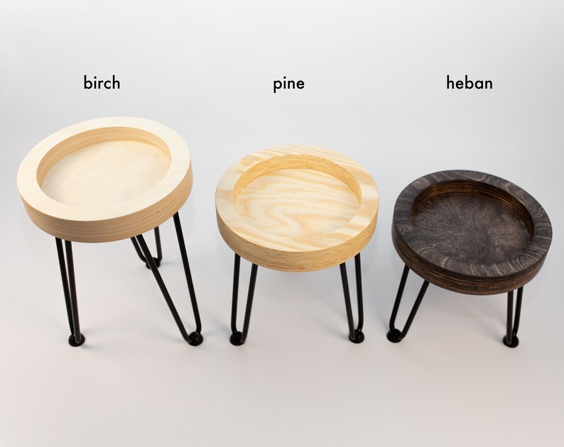 May include: Three wooden plant stands with black metal legs. The stands are made of birch, pine, and heban wood.
