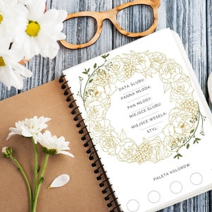 Op de afbeelding: Een wit notitieboek met een gouden bloemenontwerp op de omslag. Het notitieboek heeft een spiraalbinding en is open op een pagina met een checklist voor het plannen van een bruiloft. De checklist bevat secties voor de datum van de bruiloft, de naam van de bruid, de naam van de bruidegom, de locatie van de huwelijksceremonie, de locatie van de bruiloftsreceptie en de stijl van de bruiloft. De pagina bevat ook een sectie voor een kleurenpalet met vijf lege cirkels.