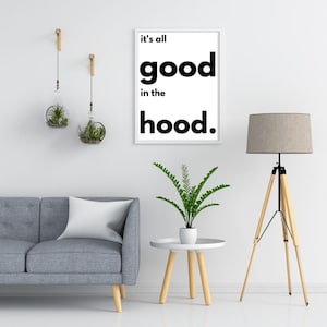 Könnte beinhalten: Ein weißer gerahmter Druck mit schwarzem Text, der "it's all good in the hood." lautet. Der Druck hängt an einer weißen Wand mit einem grauen Sofa, einem Beistelltisch, einer Topfpflanze und einer Stehlampe im Hintergrund.