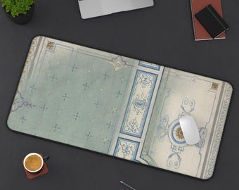 Puede incluir: Una alfombrilla de escritorio rectangular con un patrón de inspiración vintage en secciones azul claro y crema, adornada con volutas azules y pequeños detalles dorados. El diseño incluye bordes geométricos y un motivo de medallón central.