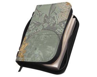 Puede incluir: Una funda para cuaderno con cremallera en color verde salvia, con un estampado estilo toile, detalles florales dorados y el texto "FRENCH" impreso en la parte frontal. La funda tiene bordes negros y contiene hojas blancas visibles.