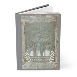 Könnte beinhalten: Ein graues Journal mit einem Vintage-inspirierten Design, das ein Gemälde einer Frau mit einer Krone und Engeln zeigt. Der Text "Journal Your Blessings" ist in Weiß auf dem Einband gedruckt.