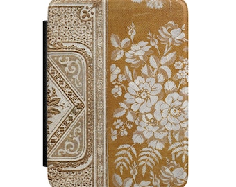Puede incluir: Una funda rectangular para lector electrónico con un diseño dividido. El lado izquierdo muestra un intrincado patrón geométrico de color crema con bordes ornamentados. El lado derecho presenta un fondo amarillo mostaza con un estampado floral blanco de rosas.