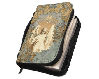 Puede incluir: Una funda de libro con cremallera que presenta una ilustración central de un ángel con alas sobre un fondo tostado, rodeado por un patrón de damasco azul y dorado. La funda tiene un cierre de cremallera negro y contiene páginas blancas.