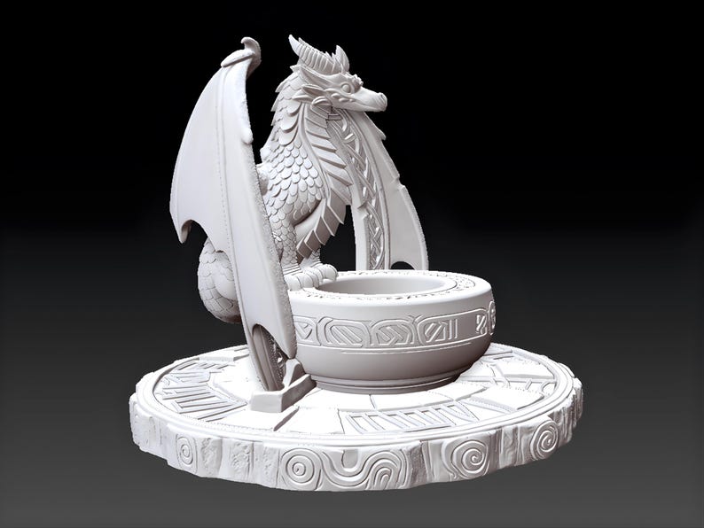 May include: A detailed, white dragon sculpture with outstretched wings, perched beside a decorative bowl. The dragon is intricately designed with scales and horns, set on a round base with carved patterns. The sculpture is a fantasy-themed decorative item.