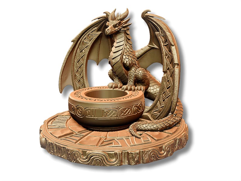 May include: A bronze-colored dragon sculpture with intricate detailing. The dragon is perched above a round bowl, with its wings spread. The base is also detailed with geometric patterns. A decorative piece.