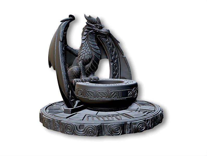 May include: A dark gray dragon sculpture with detailed scales, wings, and horns. The dragon sits atop a round, ornate base with a bowl-shaped center. The sculpture is a fantasy-themed decorative item.