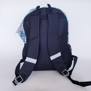 Pode incluir: Uma mochila azul marinho com um padr&atilde;o floral colorido na se&ccedil;&atilde;o superior. A mochila tem al&ccedil;as pretas, um bolso lateral de malha e faixas refletivas para seguran&ccedil;a. Uma etiqueta branca pende do topo.