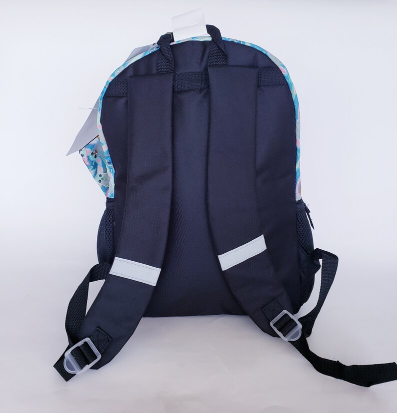 Pode incluir: Uma mochila azul marinho com um padr&atilde;o floral colorido na se&ccedil;&atilde;o superior. A mochila tem al&ccedil;as pretas, um bolso lateral de malha e faixas refletivas para seguran&ccedil;a. Uma etiqueta branca pende do topo.