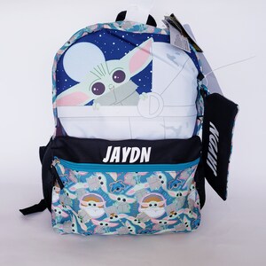 Pode incluir: Uma mochila azul com um design de Grogu de The Mandalorian. O painel superior mostra Grogu numa cena espacial. O bolso frontal tem um padr&atilde;o de Grogu e Stitch. O nome "JAYDN" est&aacute; impresso em branco na frente.