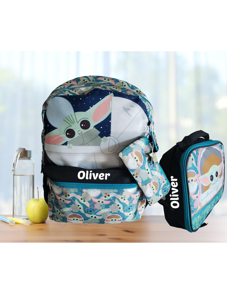 Pode incluir: Um conjunto de mochila, estojo e lancheira azuis com um design Baby Yoda. A mochila tem um gr&aacute;fico Baby Yoda e o nome "Oliver". A lancheira e o estojo tamb&eacute;m apresentam o design Baby Yoda.