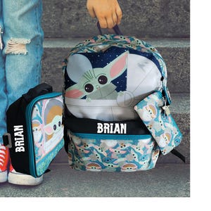 Pode incluir: Um conjunto de mochila, lancheira e estojo com um design de personagem de desenho animado. A mochila tem uma imagem grande do personagem em um fundo azul. O nome "BRIAN" &eacute; impresso.