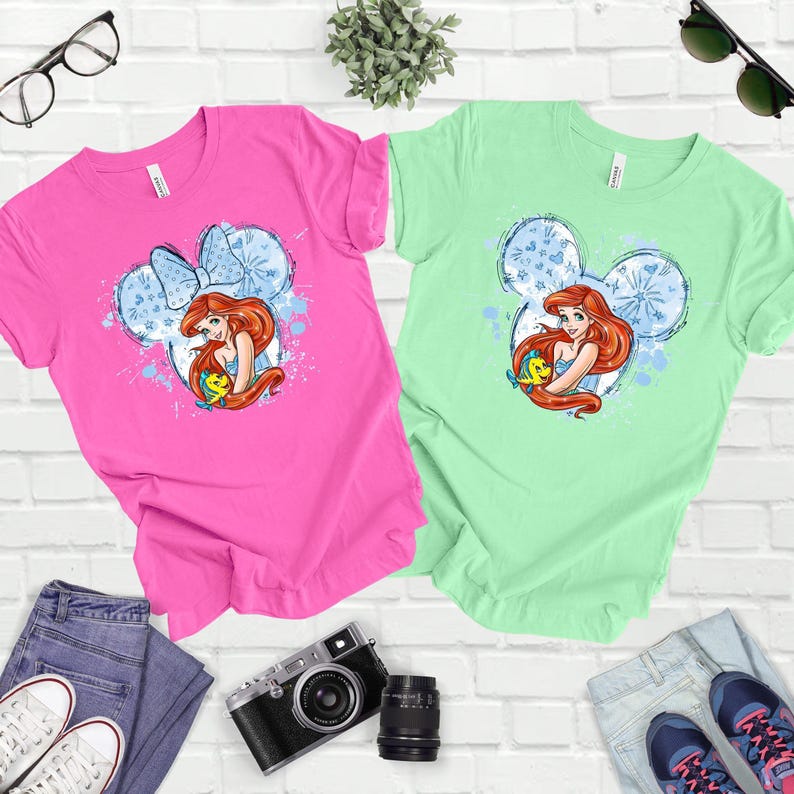 a couple of t - shirts sitting on top of a white brick wall