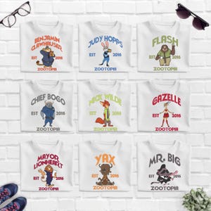 a collection of nine white t-shirts with various cartoon animal characters and text, arranged in a 3x3 grid on a white brick wall.