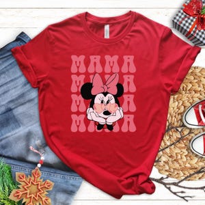 a red t-shirt with a Minnie Mouse graphic, a pair of jeans, a pair of red and white sneakers, and some Christmas decorations.