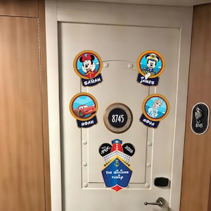 Puede incluir: Una puerta blanca con cinco pegatinas circulares que muestran personajes de Disney y nombres: Sarah con Minnie Mouse, James con Mickey Mouse, Noah con Rayo McQueen y Nova con Elsa. Una pegatina central con forma de barco dice The Williams Family 2026.