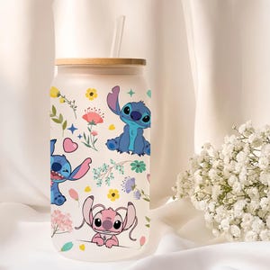 A clear glass tumbler with a lid and straw, featuring colorful illustrations of cartoon characters from the Lilo & Stitch movie franchise.