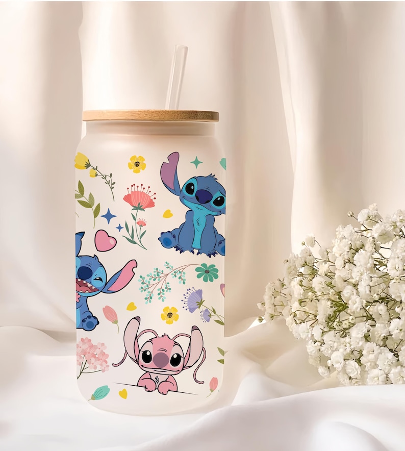 A clear glass tumbler with a lid and straw, featuring colorful illustrations of cartoon characters from the Lilo & Stitch movie franchise.