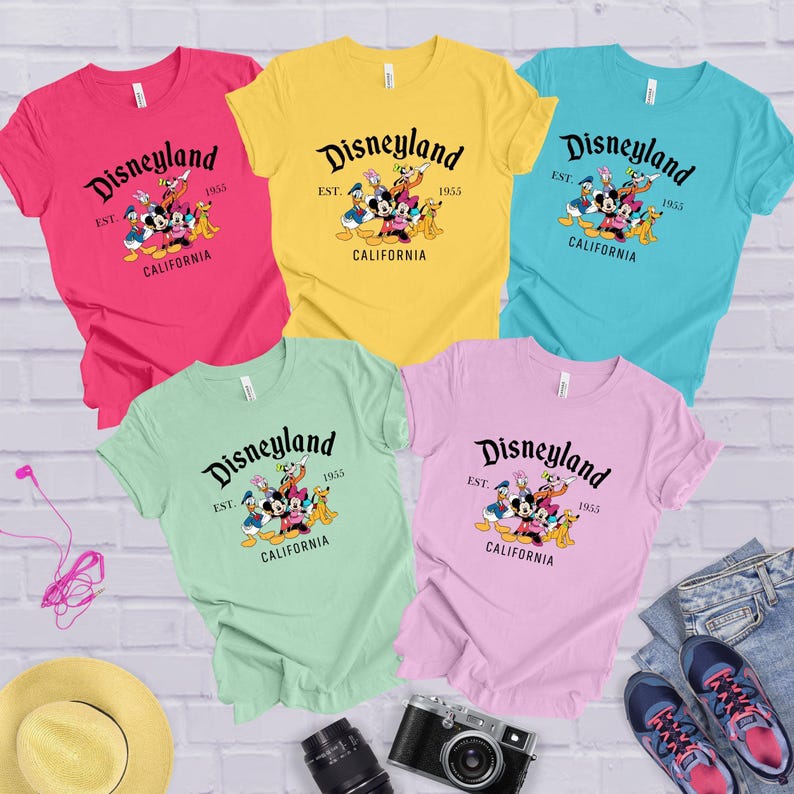 a group of disney land t - shirts sitting on top of a white brick wall