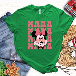 a green t-shirt with a Minnie Mouse graphic and the text "MAMA MINI" printed on it, along with a pair of jeans and a pair of red and white sneakers.