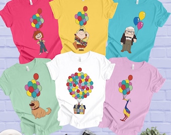 May include: Six short-sleeve t-shirts in pink, yellow, turquoise, light green, white, and light purple. Each shirt features a graphic print of characters and a house from the movie Up, including colorful balloons attached to each subject.