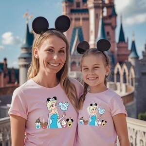 a woman and a girl wearing matching shirts in front of a castle