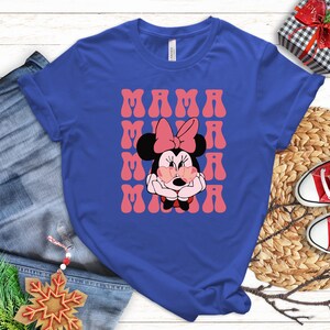 A blue t-shirt with a Minnie Mouse graphic and the text "MAMA MINNIE" printed on it, along with a pair of jeans and a pair of red and white sneakers.