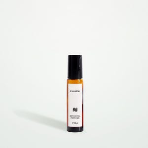 May include: A brown glass roller bottle with a black cap and a white label. The label says "PUAKENI" and "BOTANICAL PERFUME" with a stylized "N" logo. The bottle contains 10 ml of perfume.