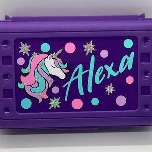 May include: Purple pencil case with a unicorn, stars, and dots design. The name "Alexa" is written in turquoise lettering.