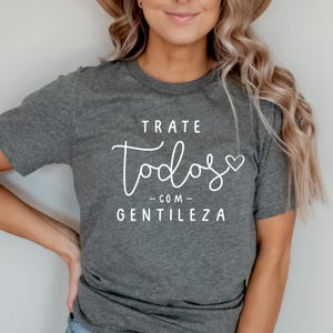 May include: Gray t-shirt with the text "TRATE TODOS COM GENTILEZA" in white lettering with a small heart.