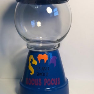May include: A blue and orange Halloween themed candy jar with the text "It's just a bunch of Hocus Pocus".