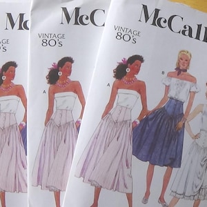 May include: A stack of McCall's vintage 80s sewing patterns. The patterns show illustrations of women in dresses. The text "McCall's" and "Vintage 80's" are printed on the pattern covers.