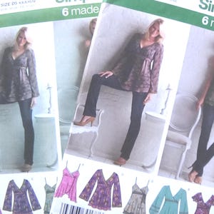 May include: Three Simplicity sewing pattern envelopes are displayed, featuring images of a woman modeling various tops and dresses. The patterns include the text "Simplicity 6 made easy" and the pattern number 3956.